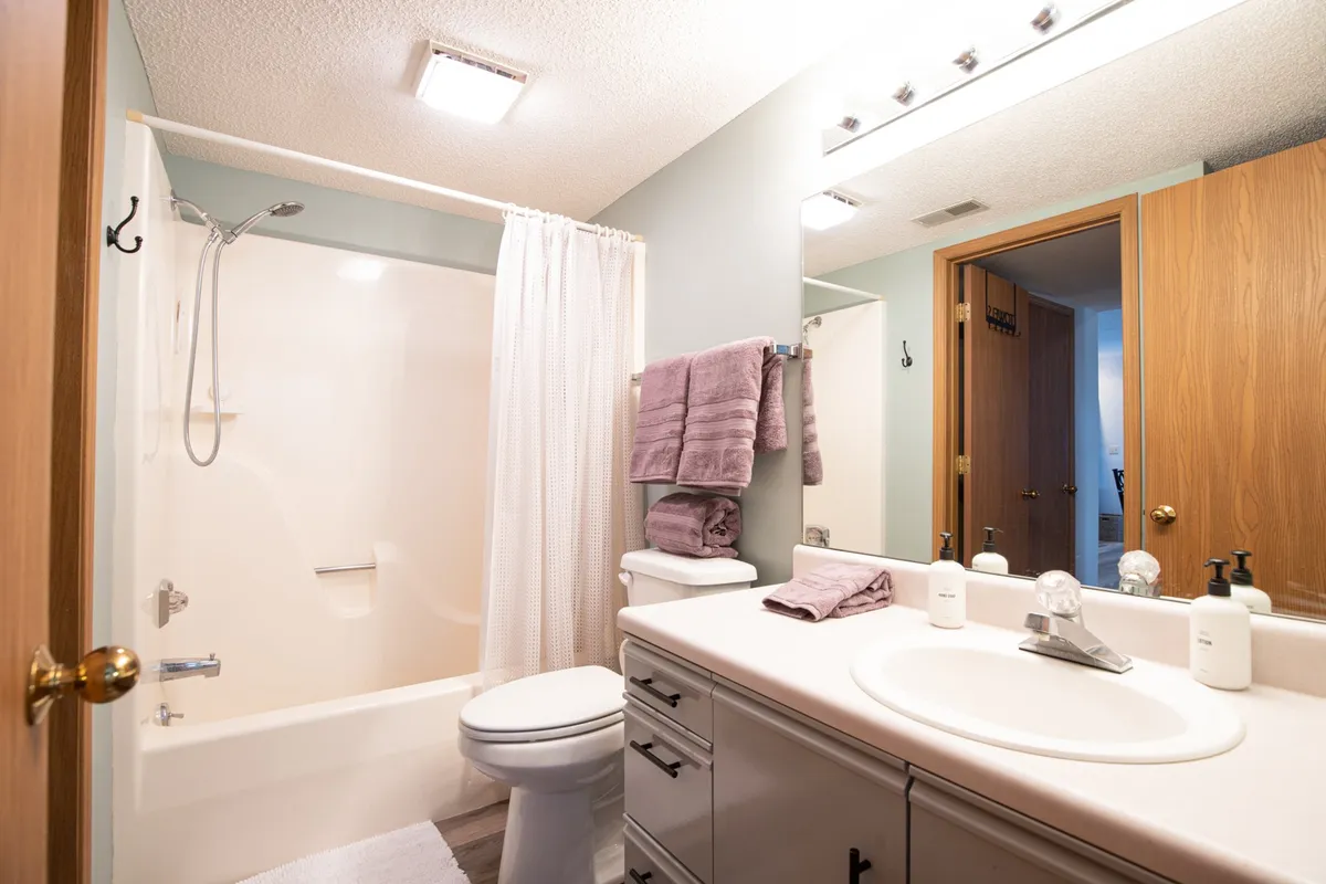 A bright, inviting full bathroom featuring a spacious vanity, modern shower area, and neatly arranged towels. Soft lighting and fresh decor enhance the mood of relaxation and convenience.