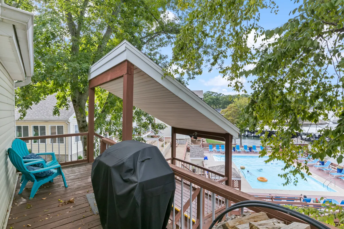A wooden deck with a grill, blue Adirondack chair, swimming pool, and several lounge chairs. The space is well-suited to barbecues, sunbathing, and poolside gatherings—perfect for active family experiences.
