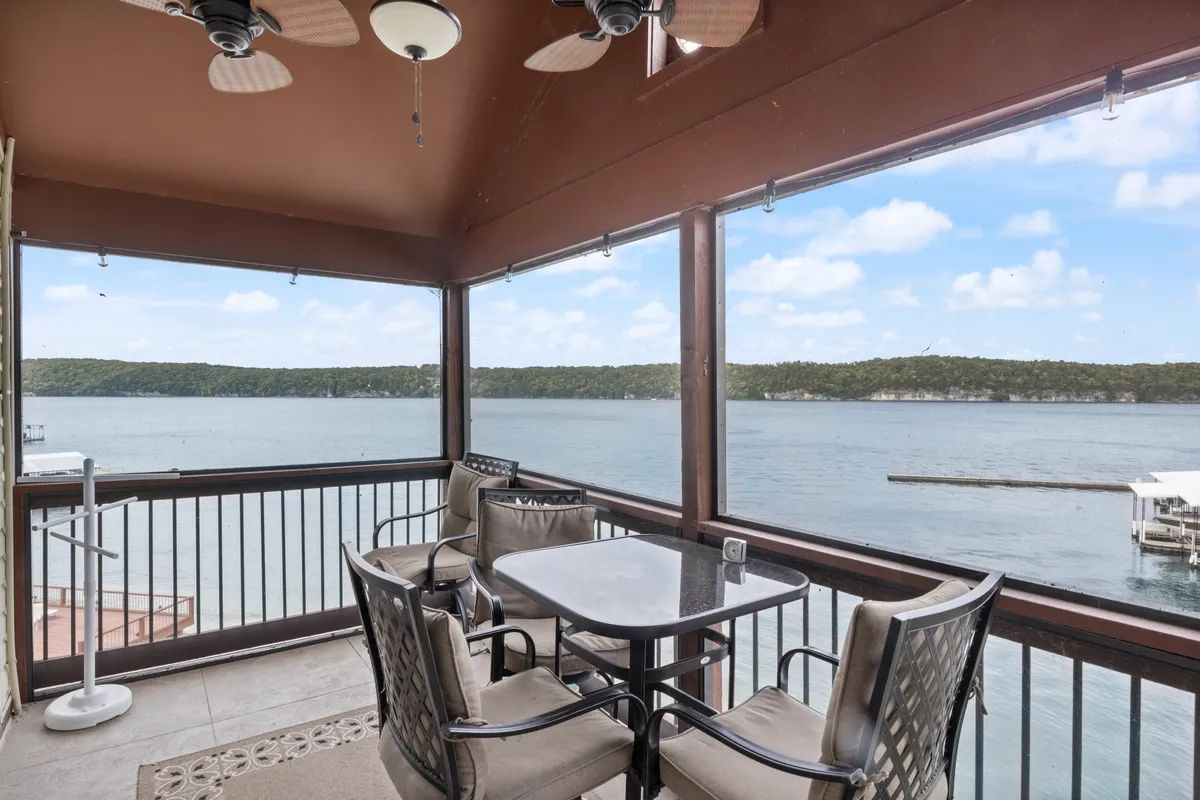 A serene outdoor dining area featuring a table, lake views, and ceiling fans. The setup provides a comfortable space for meals, conversation, and enjoying sunsets as a family.